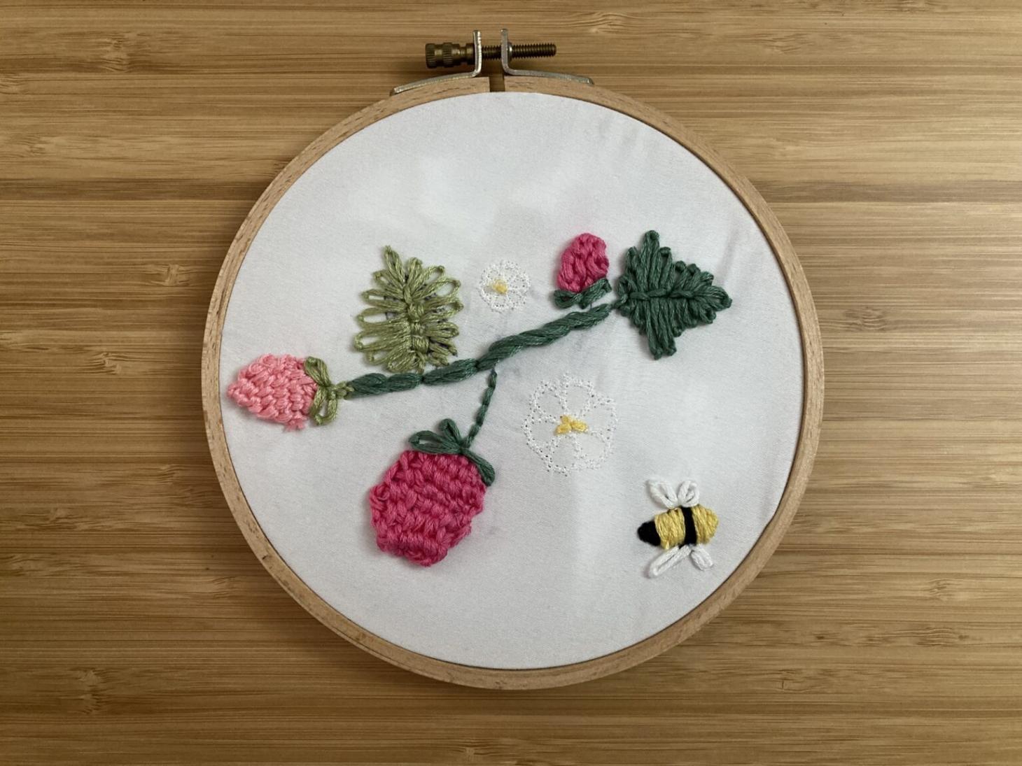 a student stitched plants with code, then hand embroidered a bee.